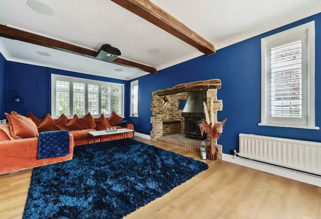 A character living room with exposed beams, blue walls and an orange sofa in a Horsham home